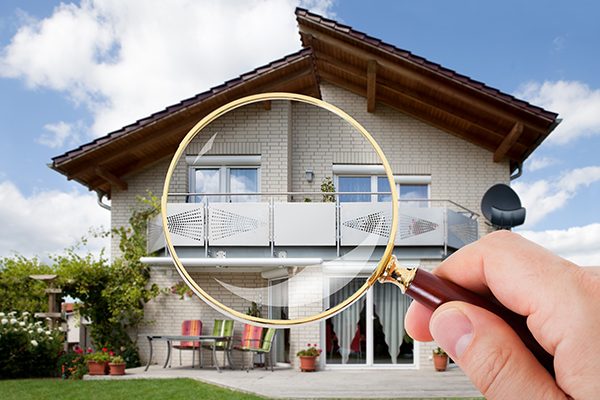 Hand With Magnifying Glass Over House
